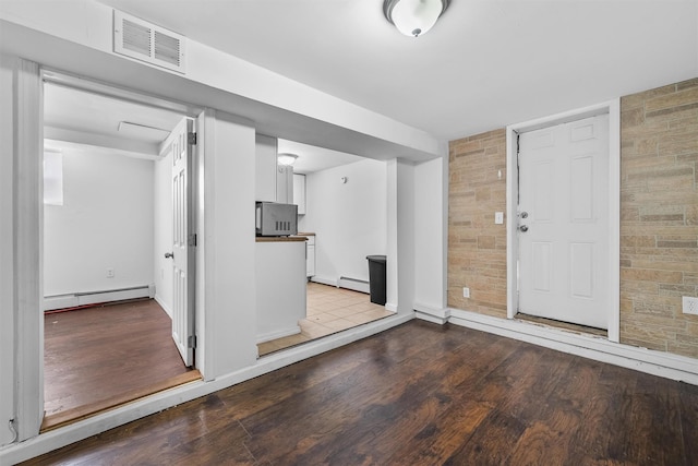 interior space featuring visible vents, a baseboard heating unit, baseboards, and wood finished floors