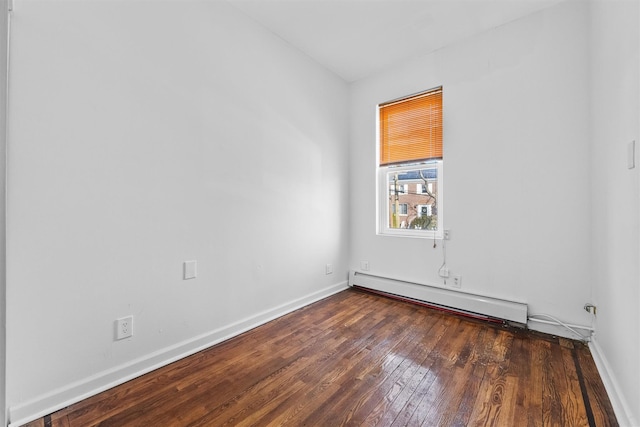 empty room featuring baseboard heating, baseboards, and hardwood / wood-style flooring