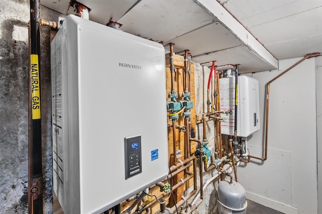 utility room featuring tankless water heater and water heater