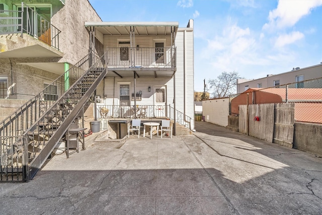 back of house featuring stairway, a patio, and fence