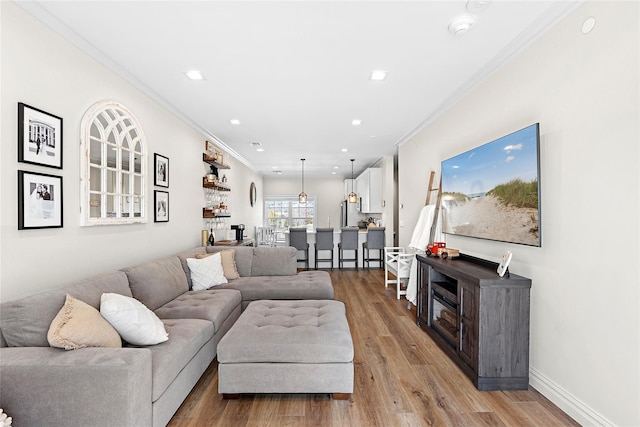 living area featuring recessed lighting, baseboards, ornamental molding, and light wood finished floors