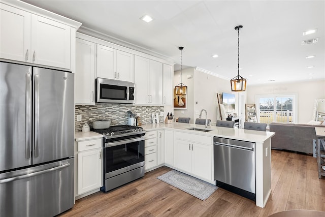 kitchen with visible vents, a peninsula, a sink, stainless steel appliances, and open floor plan