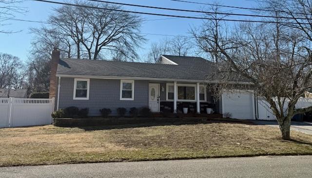 ranch-style house with a front lawn, an attached garage, and fence