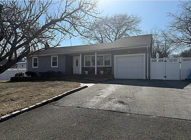 ranch-style house featuring driveway, a gate, fence, covered porch, and an attached garage