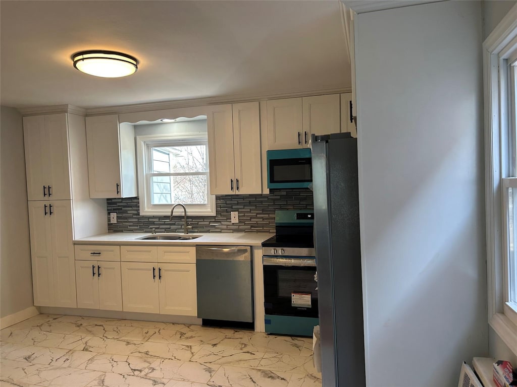 kitchen with marble finish floor, appliances with stainless steel finishes, light countertops, and a sink