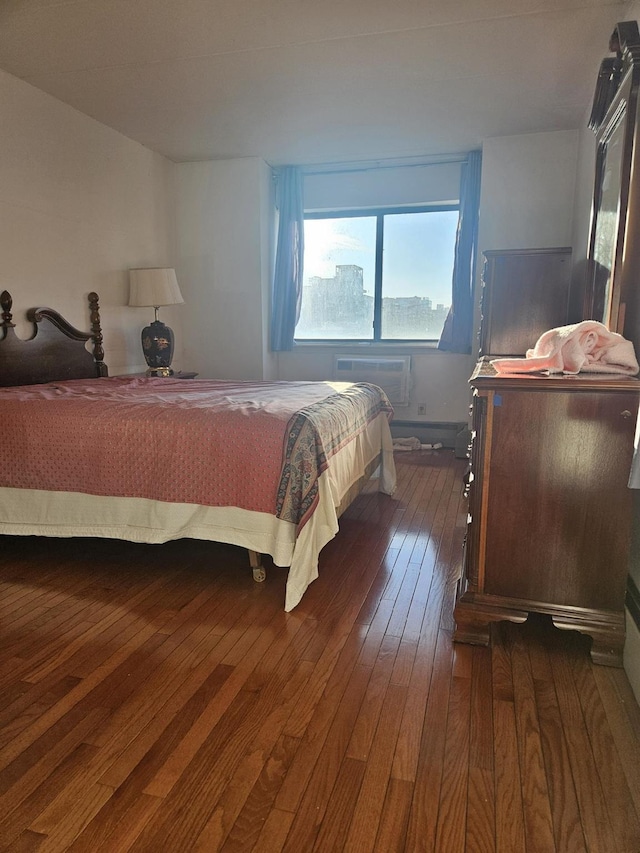 bedroom featuring dark wood finished floors and a wall unit AC