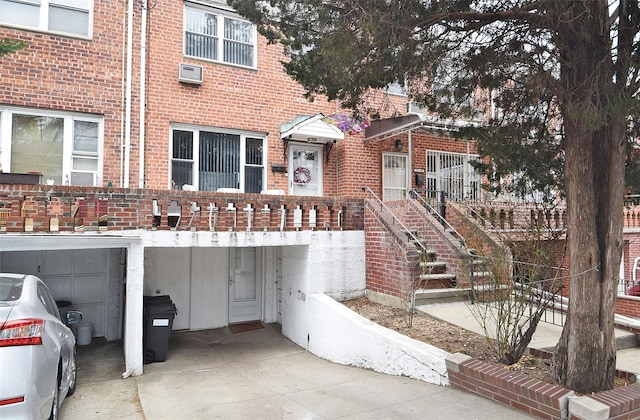 view of front of house with a wall mounted air conditioner, brick siding, and driveway