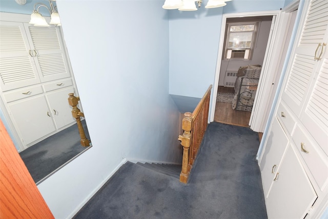 corridor featuring an upstairs landing, dark carpet, and baseboards