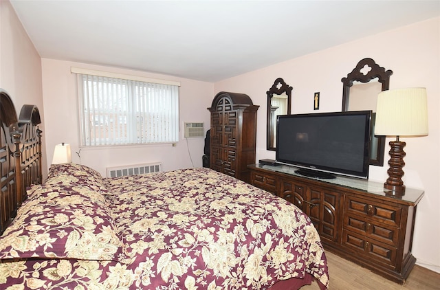 bedroom with a wall mounted air conditioner, light wood-type flooring, and visible vents