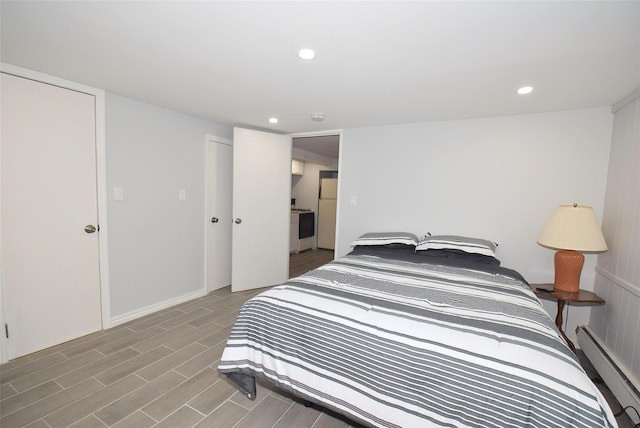 bedroom featuring recessed lighting, a baseboard heating unit, and wood finished floors