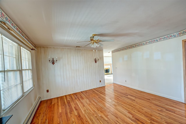 unfurnished room featuring baseboards, light wood-type flooring, a ceiling fan, and a baseboard radiator