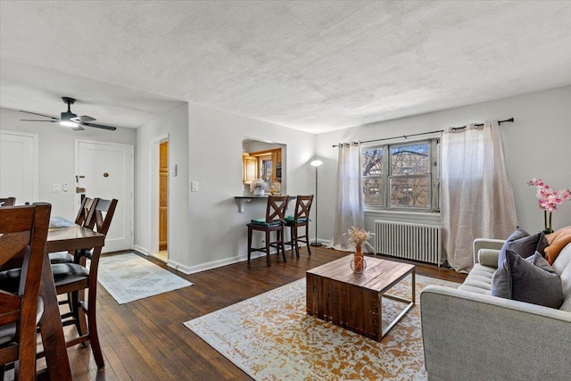 living room with baseboards, radiator heating unit, hardwood / wood-style flooring, a textured ceiling, and a ceiling fan