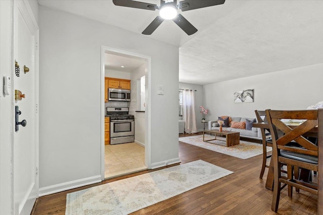 interior space featuring ceiling fan, baseboards, and wood finished floors