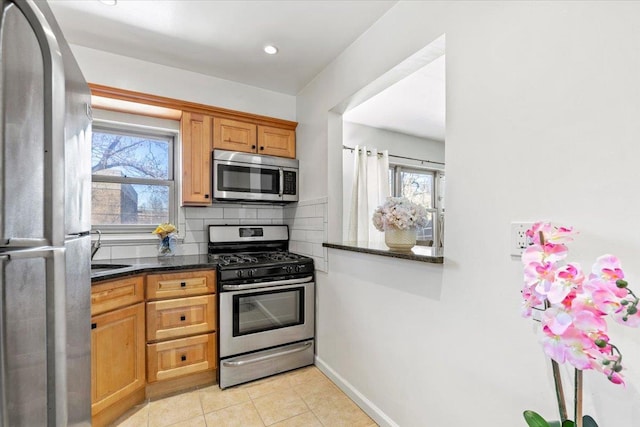 kitchen featuring decorative backsplash, a healthy amount of sunlight, appliances with stainless steel finishes, and baseboards