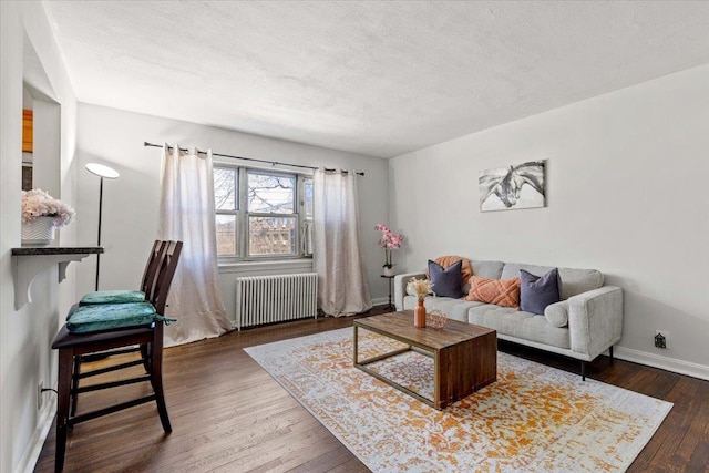 living room with hardwood / wood-style flooring, radiator, baseboards, and a textured ceiling