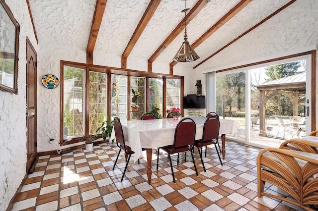 dining room with vaulted ceiling with beams and a textured wall