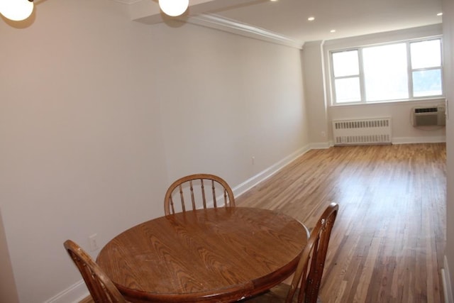 dining area featuring a wall unit AC, wood finished floors, baseboards, radiator heating unit, and recessed lighting