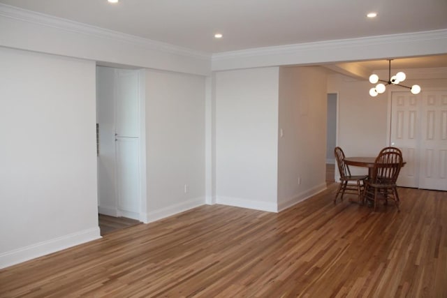 unfurnished dining area featuring a notable chandelier, wood finished floors, and crown molding