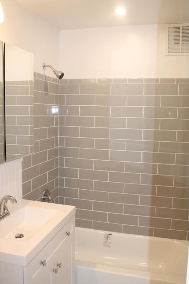 full bath with visible vents, vanity, tile walls, and  shower combination