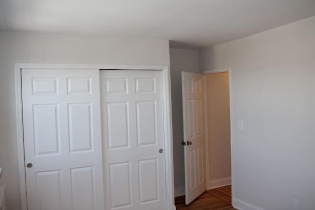 unfurnished bedroom featuring a closet, baseboards, and wood finished floors