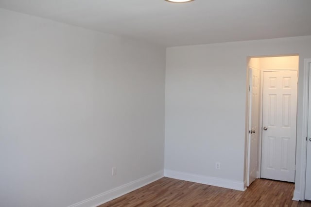 spare room featuring baseboards and wood finished floors