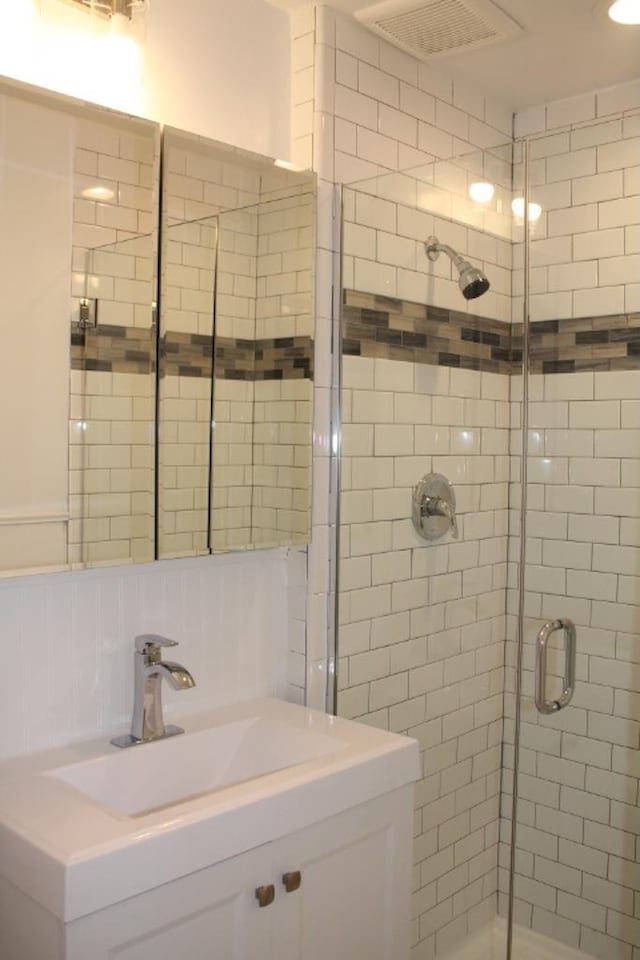 bathroom with visible vents, a shower stall, decorative backsplash, and a sink