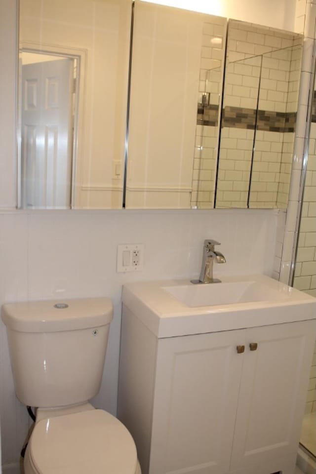 full bath with toilet, tile walls, and vanity