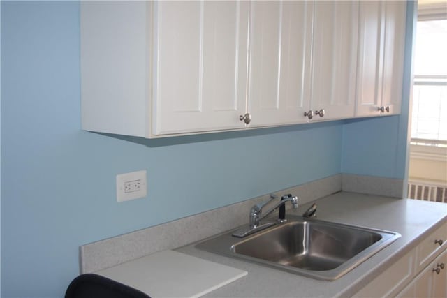 kitchen with light countertops, white cabinets, and a sink