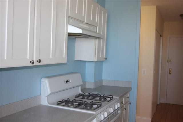 kitchen featuring light countertops, white cabinets, gas range gas stove, and under cabinet range hood