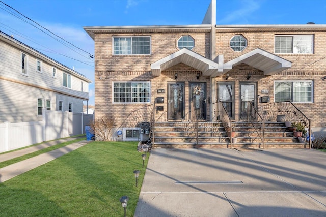 view of front of home featuring a front yard, fence, and brick siding