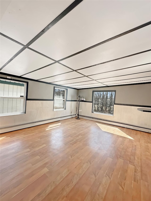 unfurnished room with a wainscoted wall, wood finished floors, and a baseboard radiator