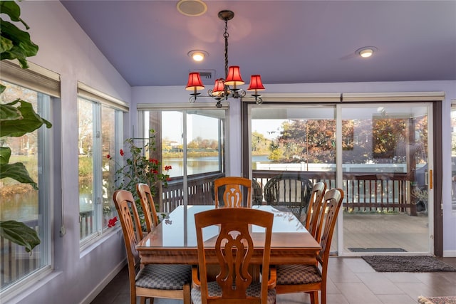 dining area with visible vents, a water view, lofted ceiling, baseboards, and a chandelier