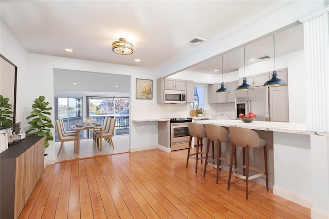 kitchen featuring electric range, visible vents, tasteful backsplash, a breakfast bar area, and light wood finished floors