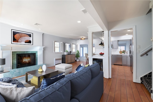 living room with visible vents, wood finished floors, a fireplace, and radiator heating unit