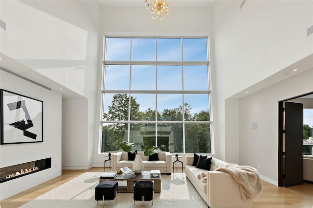 68 Root Ave, Carmel, NY 10509 - living area featuring a towering ceiling, a glass covered fireplace, wood finished floors, a chandelier, and recessed lighting