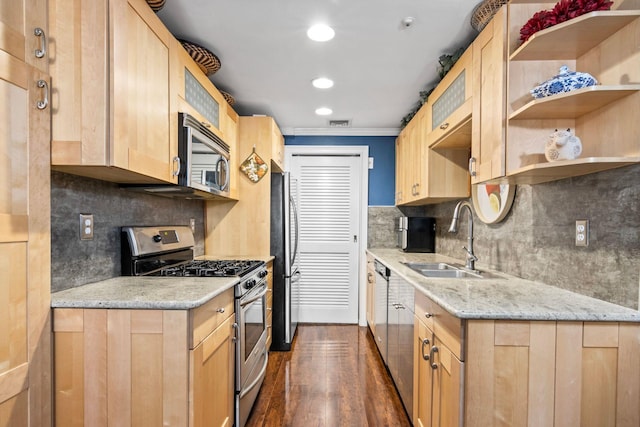 kitchen with light brown cabinetry, stainless steel appliances, and a sink