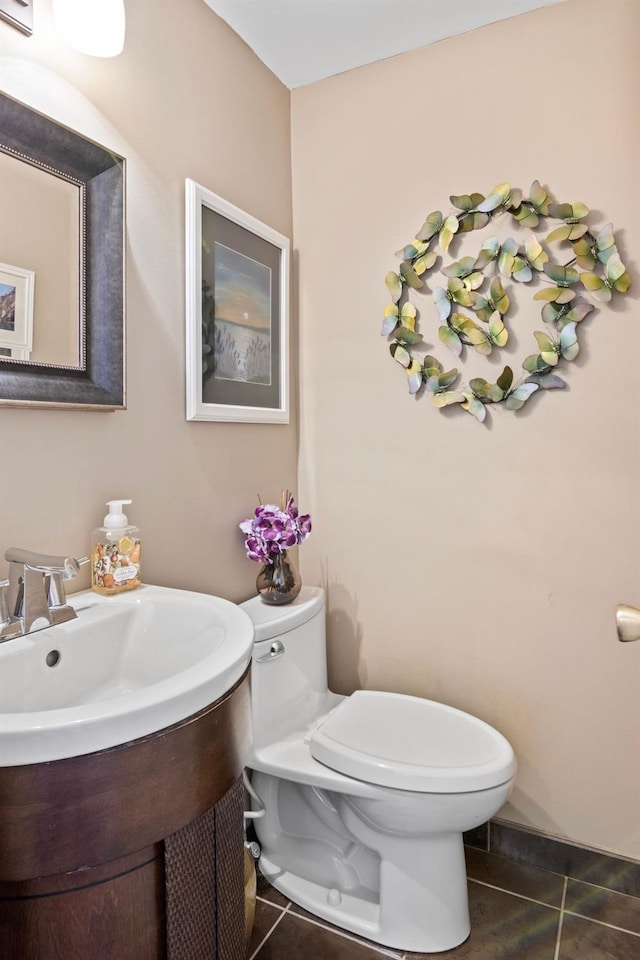 half bath featuring tile patterned flooring, toilet, and vanity