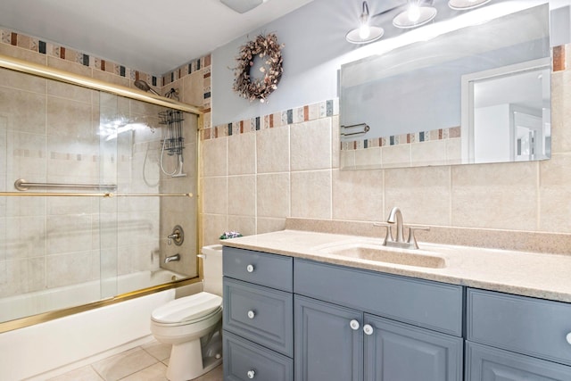 bathroom featuring vanity, shower / bath combination with glass door, tile patterned flooring, tile walls, and toilet