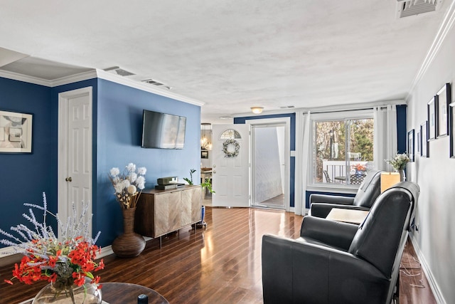 living area with crown molding, wood finished floors, visible vents, and baseboards