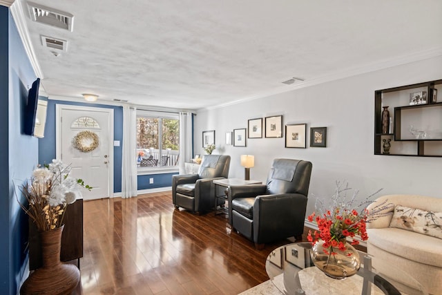 living area featuring crown molding, wood finished floors, visible vents, and baseboards