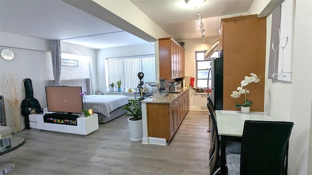 kitchen featuring light wood-type flooring, brown cabinets, open floor plan, freestanding refrigerator, and light countertops