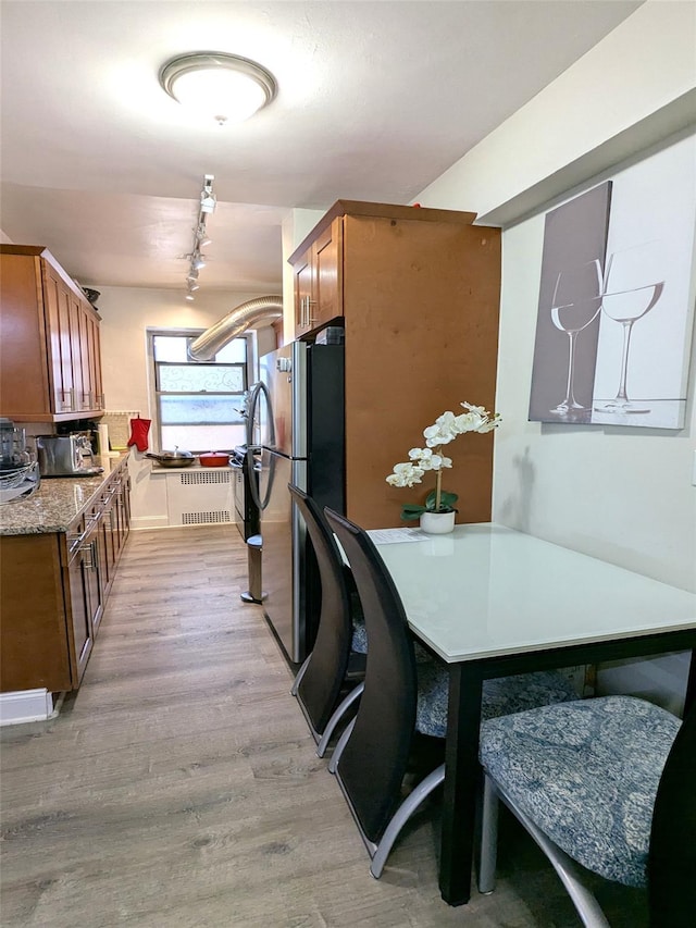 kitchen with brown cabinets, light wood-type flooring, and freestanding refrigerator