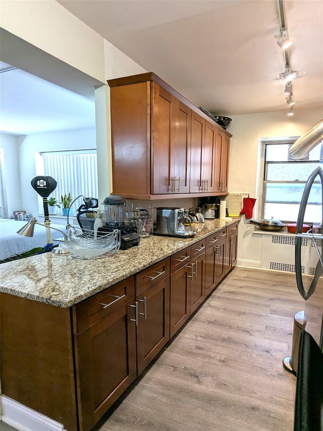 kitchen featuring light stone counters, track lighting, and light wood-style flooring