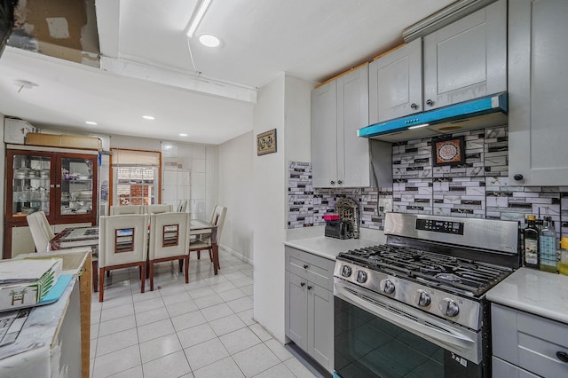 kitchen featuring under cabinet range hood, tasteful backsplash, stainless steel range with gas stovetop, and light countertops