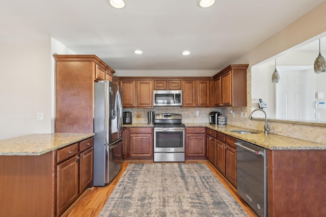 kitchen with a sink, a peninsula, decorative backsplash, and stainless steel appliances