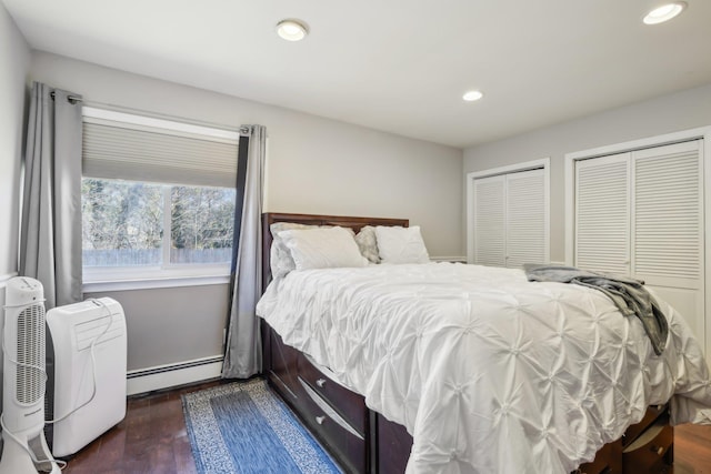 bedroom with dark wood-type flooring, recessed lighting, multiple closets, and a baseboard radiator