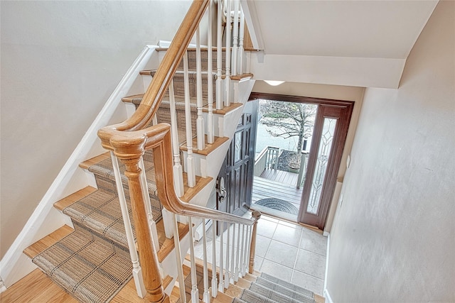 stairway with tile patterned flooring, lofted ceiling, and baseboards