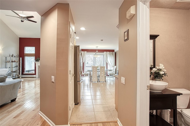 corridor with light wood-type flooring and baseboards