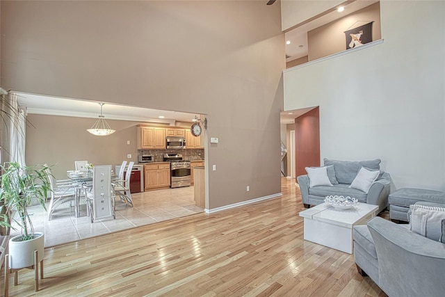 living room featuring recessed lighting, baseboards, a high ceiling, and light wood-style floors