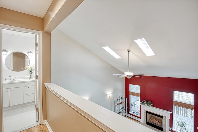 details with ceiling fan, a fireplace, a skylight, wood finished floors, and a sink